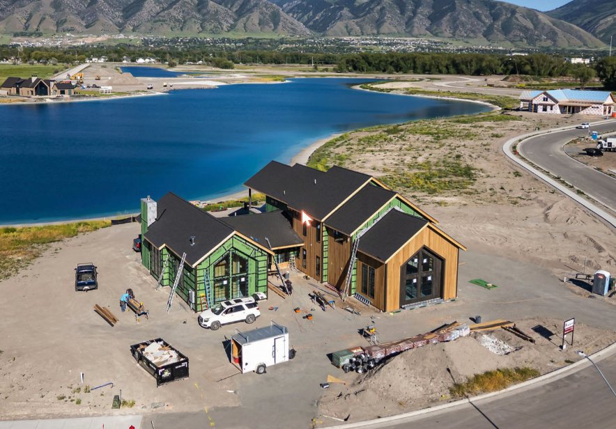 A custom home framing up on the shoreline at Willow Lakes, Utah — an example of the community's mountain-lake style