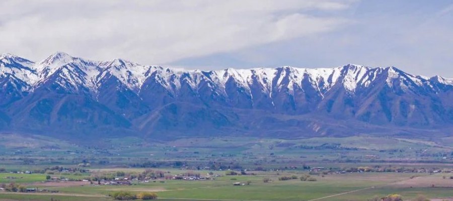 The snow-capped Wellsville Mountains rising above a green Northern Utah valley